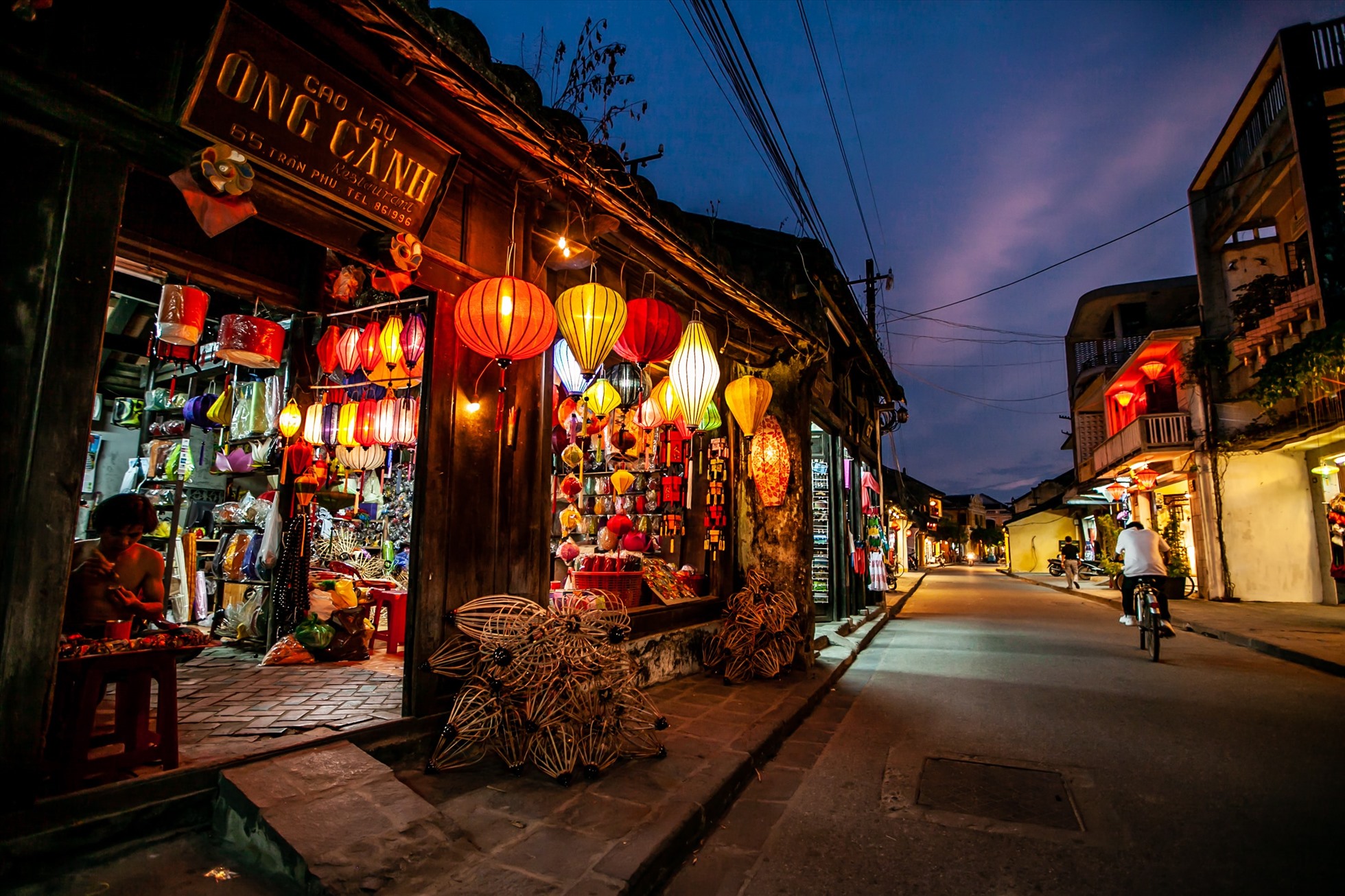 Cyclists exploring quiet streets of Hoi An old town at night