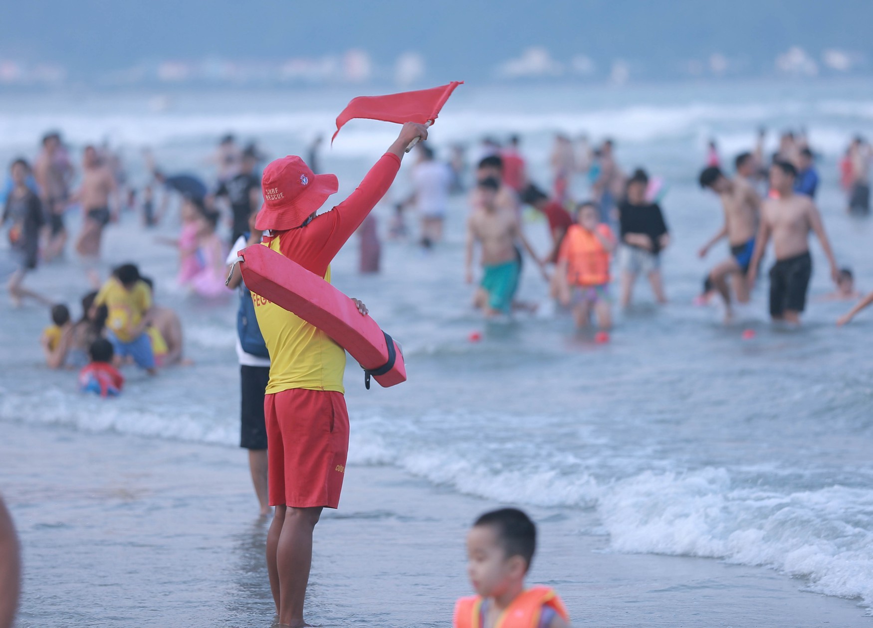 Lifeguards on duty and safety flags marking swimming zones along the beach.