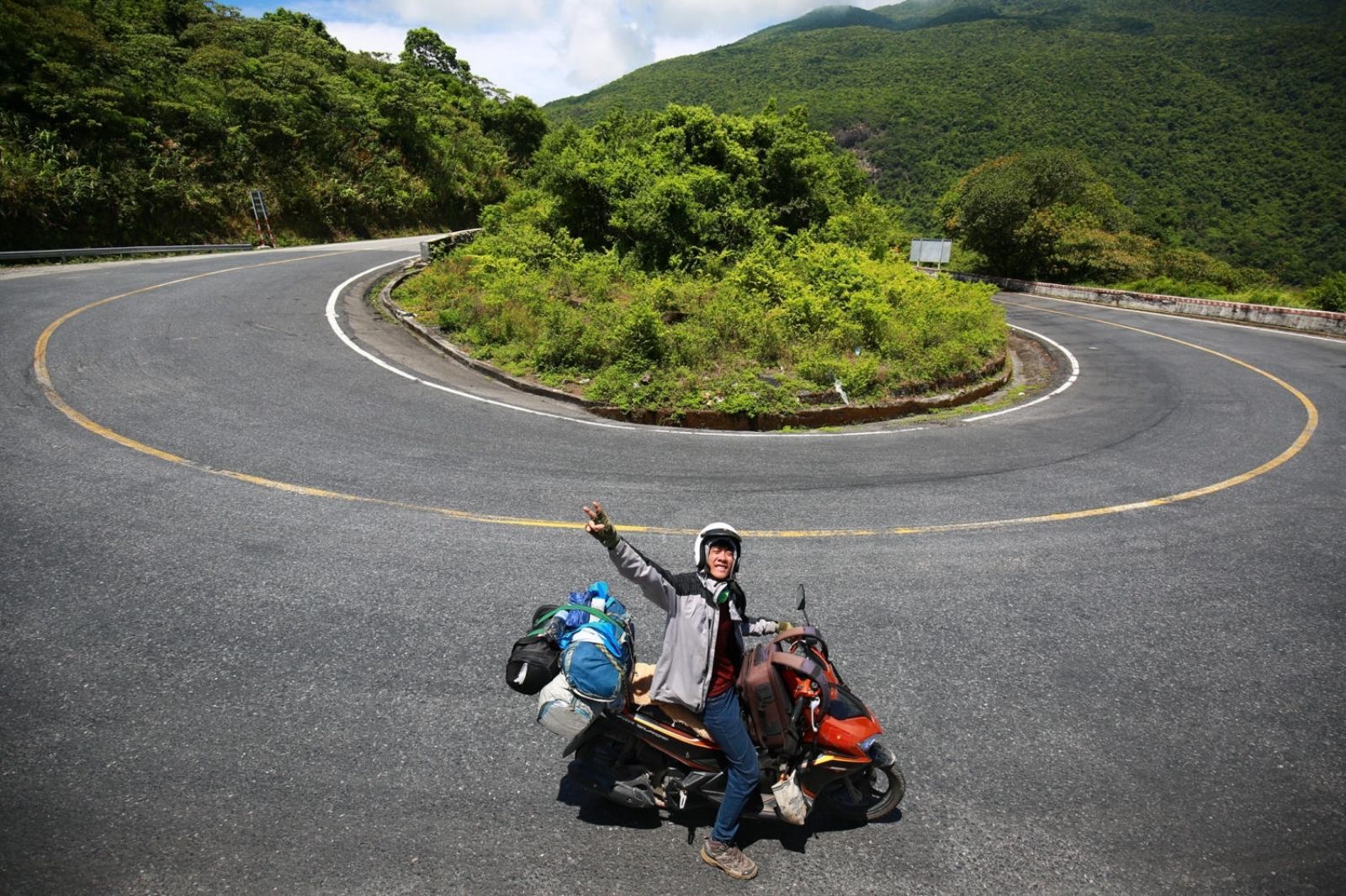 Motorbike rider navigating a winding coastal mountain road in Vietnam
