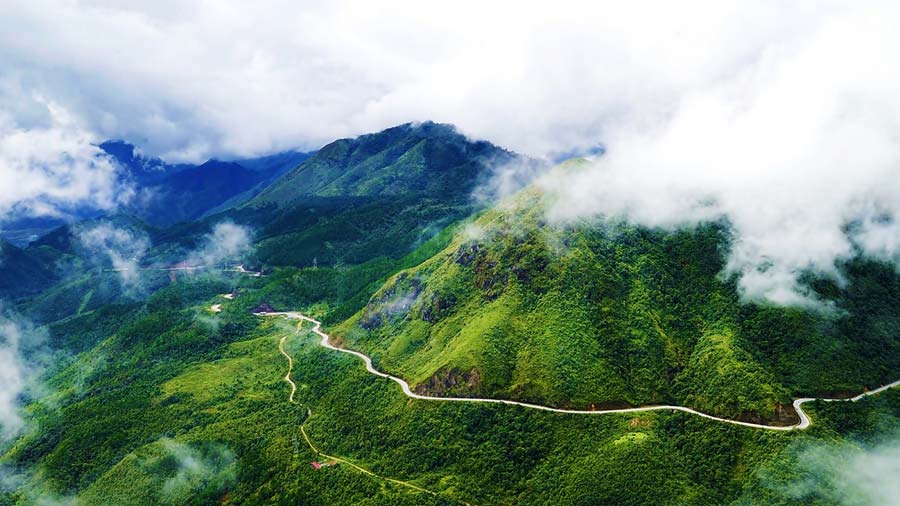 Panoramic aerial view of a winding coastal mountain pass with ocean and clouds in central Vietnam